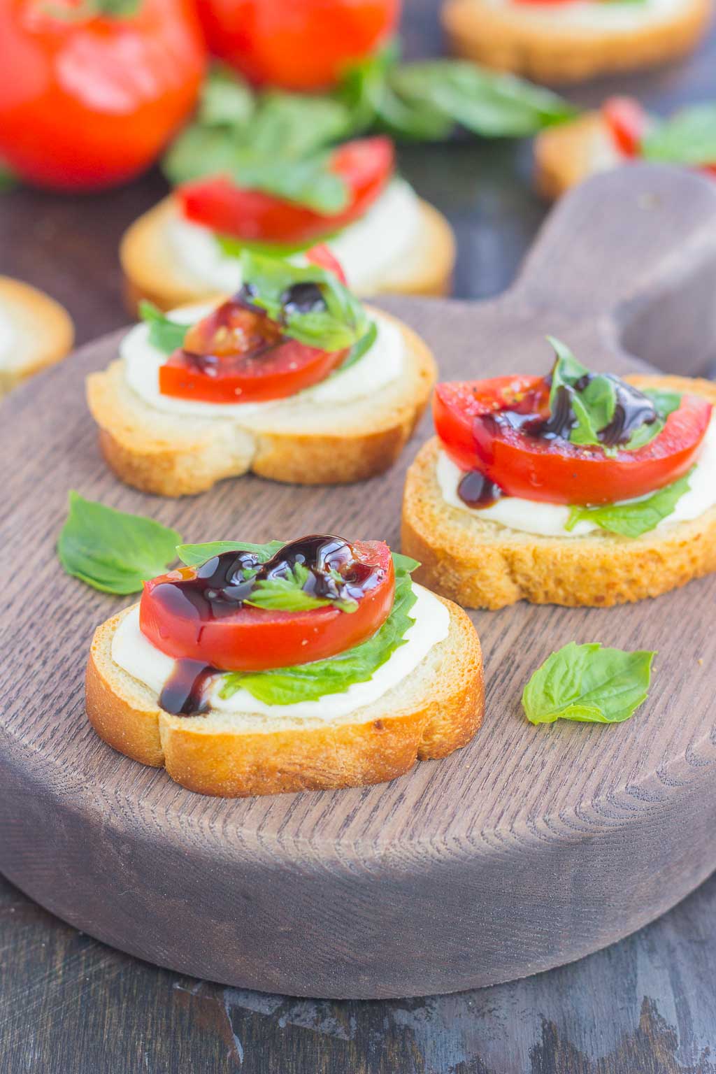 Three caprese bites on a wood charcuterie board.