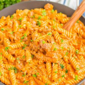pasta in a black skillet with a wooden spoon